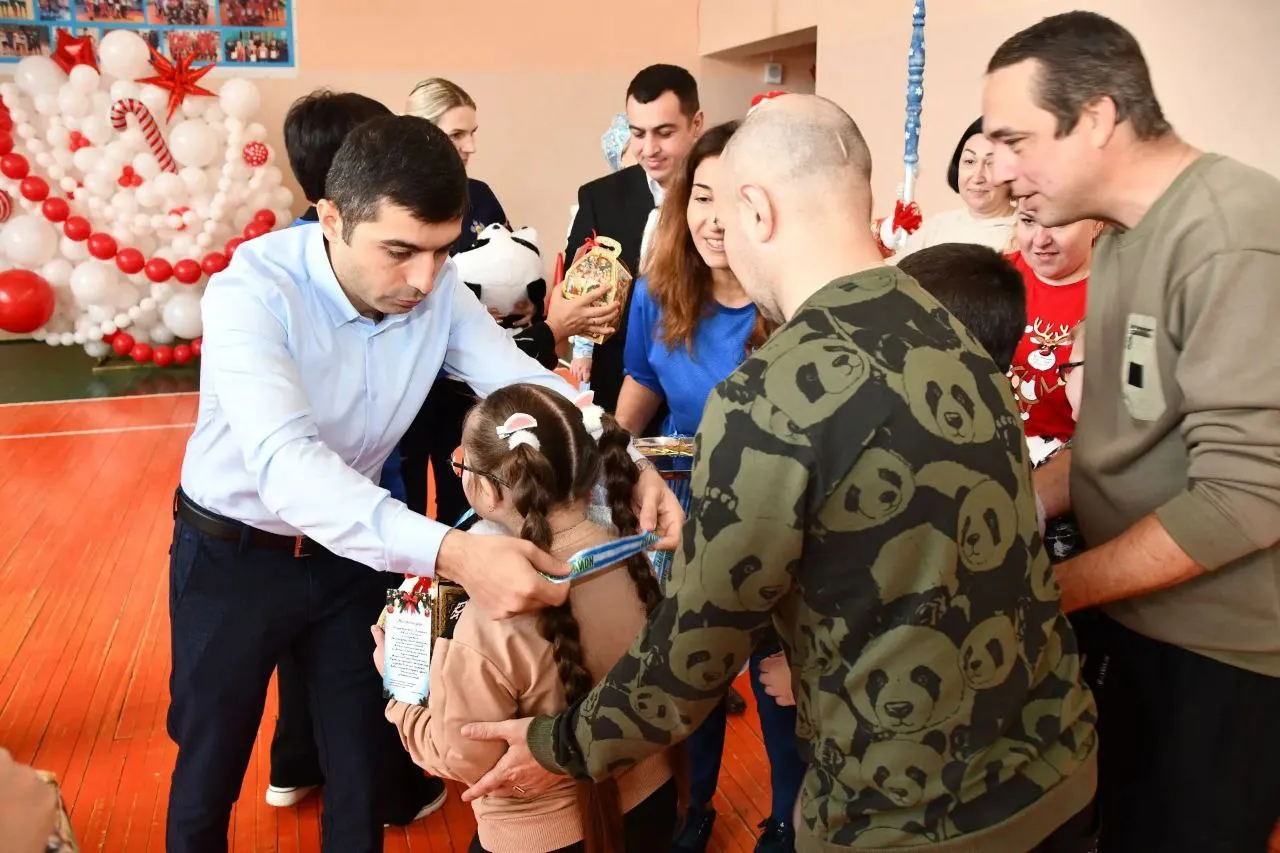 Хачатур Херумян вручает медаль девочке с косичками в спортивном зале