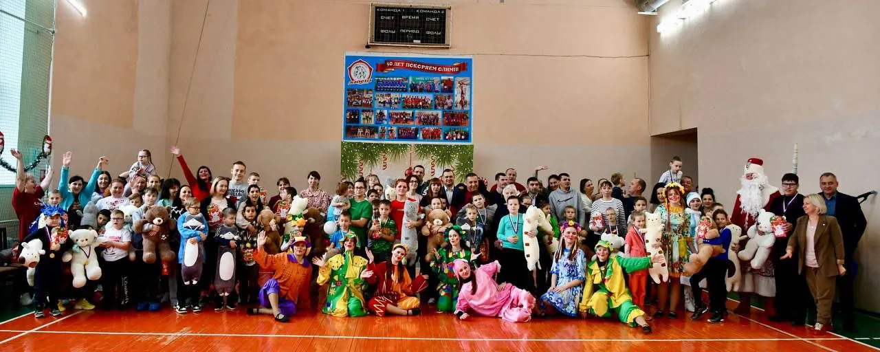 Широкая панорама спортивного зала с участниками новогоднего мероприятия