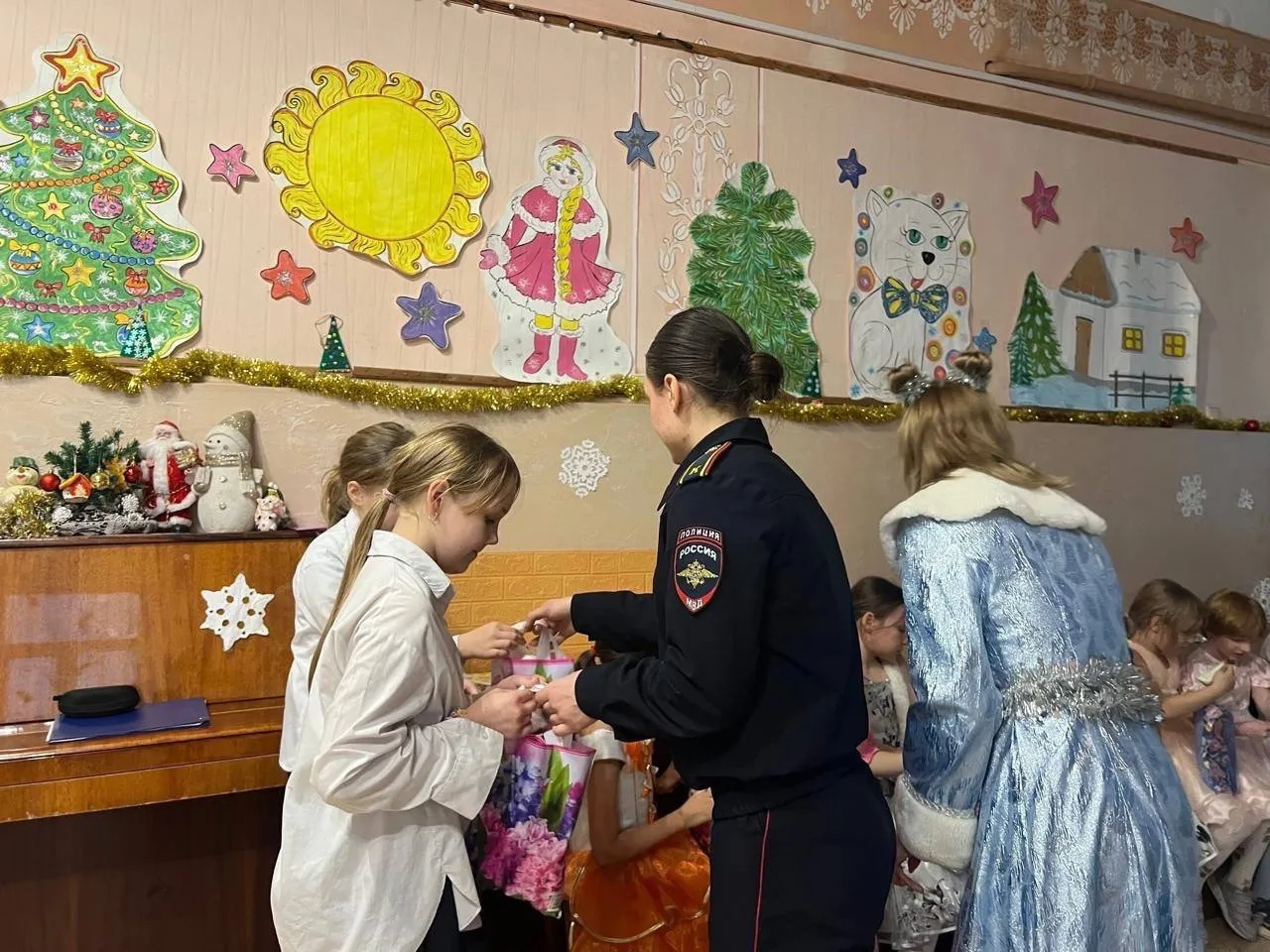 Сотрудница полиции вручает подарок девочке на новогоднем празднике